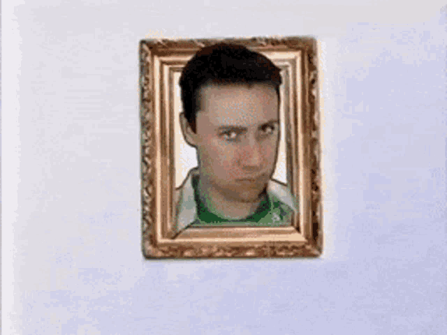 a picture of a man in a green shirt in a gold frame on a wall