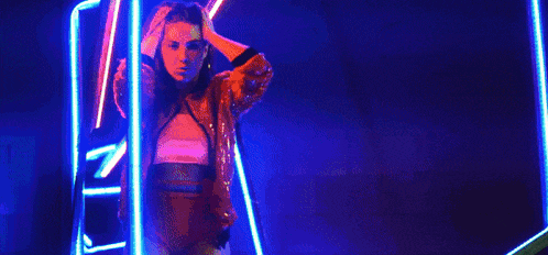a woman in a red jacket and red shorts is standing in front of a neon sign .