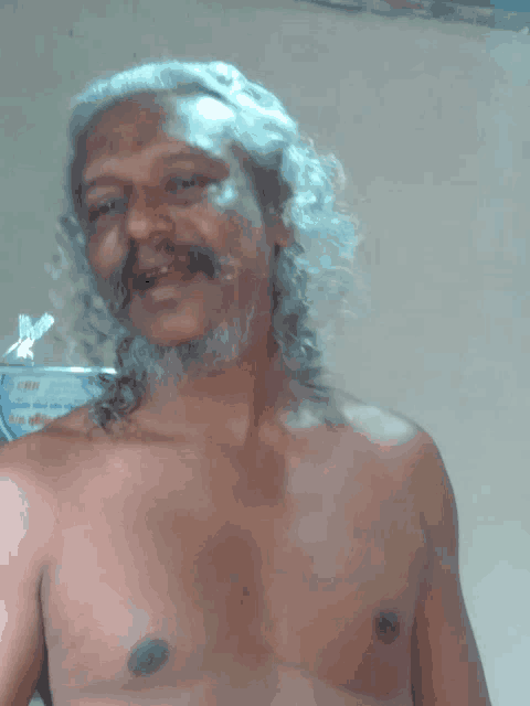 a shirtless man with long hair and a beard is smiling for the camera