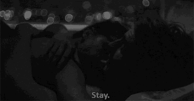 a black and white photo of a man and woman laying in bed with the words " stay " written on the bottom