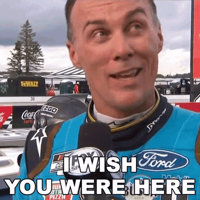 a man wearing a blue ford shirt is talking into a microphone