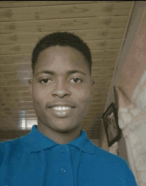 a young man wearing a blue shirt is smiling for the camera