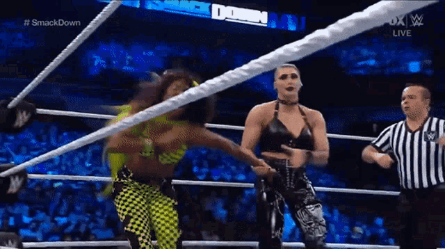 two women are wrestling in a ring while a referee watches