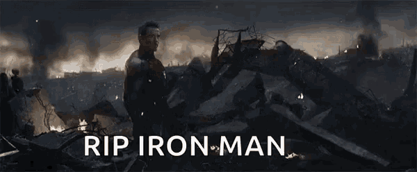 a man in a suit is standing in a pile of rubble with the words `` rip iron man '' written on the bottom .