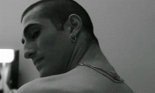 a man with a chain around his neck and earrings on his ears