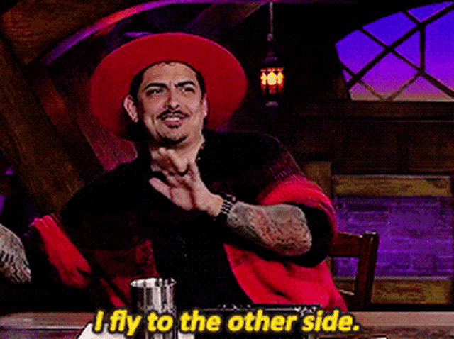 a man in a red hat says " i fly to the other side " while sitting at a table