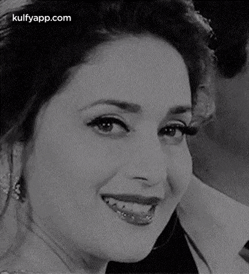 a black and white photo of a woman smiling with her mouth open .