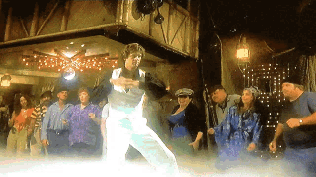 a group of people are dancing in a room with a disco ball in the background