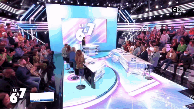 a group of people are sitting in front of a stage with the number 67 on it