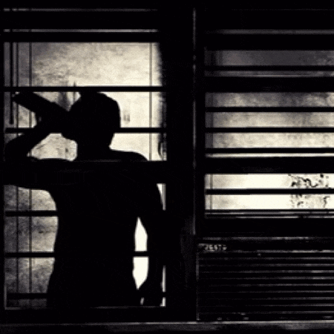 a silhouette of a man standing in front of a window .