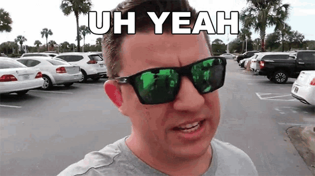 a man wearing sunglasses says uh yeah in front of a parking lot full of cars