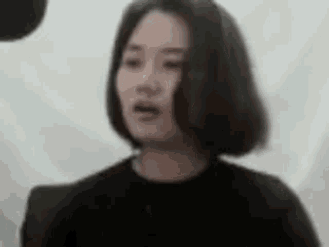 a woman with short hair is wearing a black shirt and a black necklace .