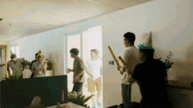 a group of people wearing party hats and holding sticks in a room