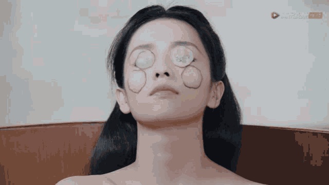 a woman with circles drawn on her face is laying in a bath tub