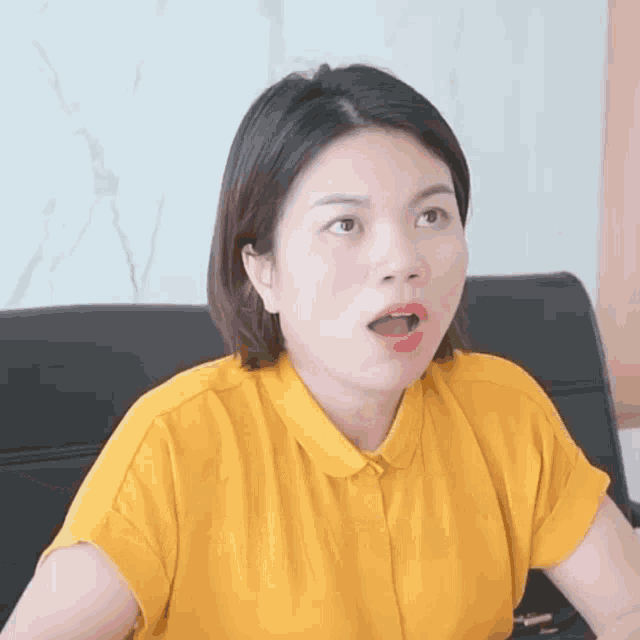 a woman in a yellow shirt is making a funny face