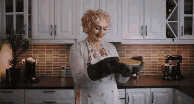 a woman in a kitchen holding a pie in her hands