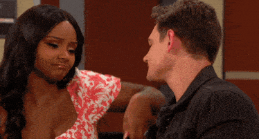 a man and a woman are looking at each other in front of a sign that says ' elevators '