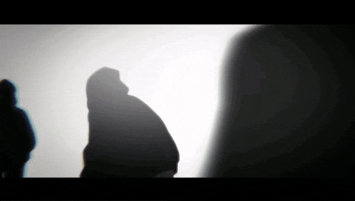 a shadow of a person in a hooded jacket is cast on a white background