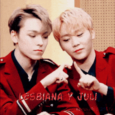two young men in red jackets are making a heart shape with their fingers and the words lesbiana y juli are visible behind them