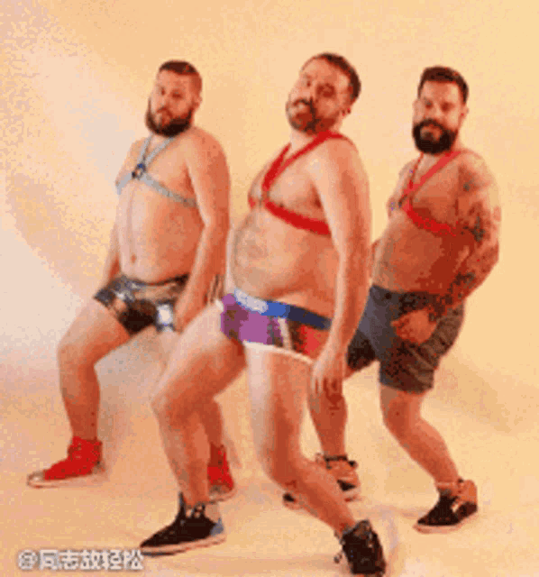 three men in underwear are dancing in front of a wall