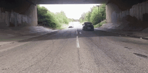 a black car is driving under a bridge on a highway