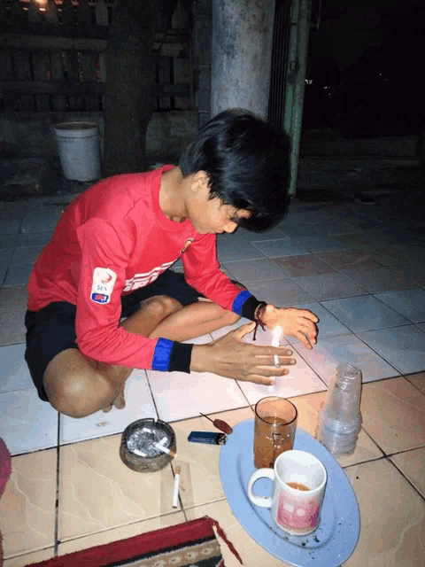 a man wearing a red shirt that says ' sd ' on it sits on the floor