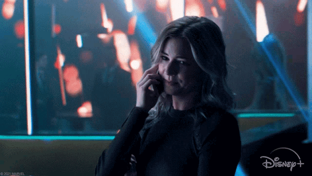 a woman talking on a cell phone with a disney + logo in the background