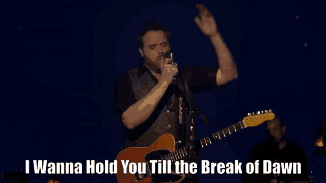a man singing into a microphone with the words i wanna hold you till the break of dawn written below him