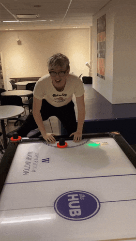 a man playing air hockey with a university of washington logo