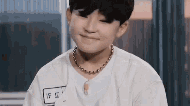 a young boy wearing a necklace and a white shirt is smiling .