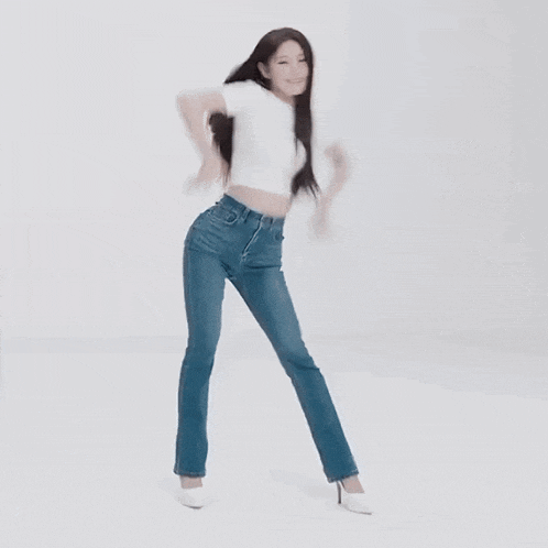 a woman in a white shirt and blue jeans is dancing in a white room .
