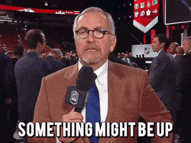 a man in a suit and tie is holding a microphone that says snl on it