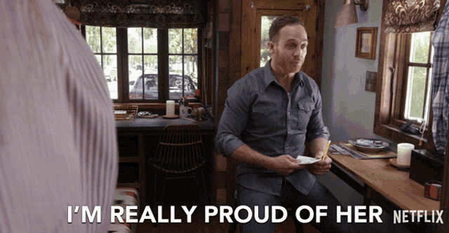 a man sitting at a table with the words i 'm really proud of her netflix on the bottom