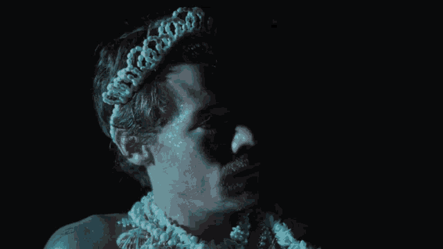 a man with a crown on his head is wearing a necklace of pearls