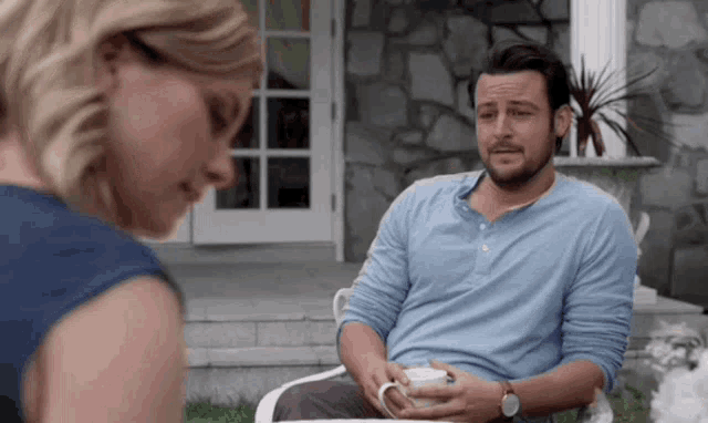 a man in a blue shirt is sitting in a chair with a woman .