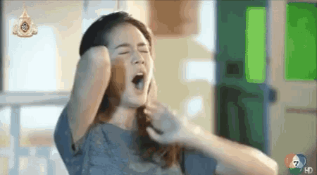 a woman is yawning with her mouth open while holding her hair in her hands .