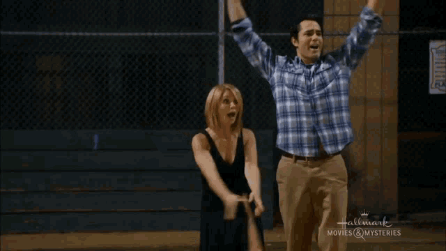 a man and a woman are standing in front of a chain link fence with the words hallmark movies & mysteries on the bottom
