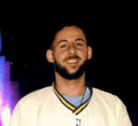 a man with a beard is wearing a white shirt with a yellow and blue collar and smiling .