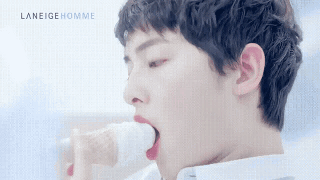a young man is eating an ice cream cone with laneige homme written on the bottom