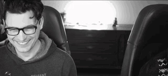 a man wearing glasses and a sweatshirt that says defiant smiles