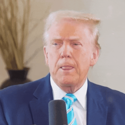 donald trump is wearing a blue suit and tie while speaking into a microphone