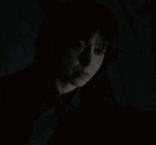 a woman 's face is shown in the dark with her eyes closed