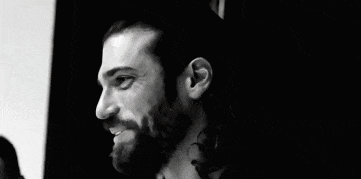 a black and white photo of a man with long hair and a beard smiling .