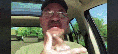 a man wearing glasses and a hat is sitting in a car