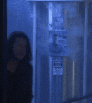 a woman with long hair is standing in a dark room with a blue background