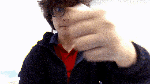 a man wearing glasses and a red polo shirt holds his fist up in the air