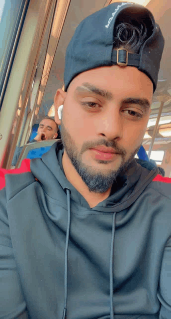 a man with a beard wearing a black hat that says reebok on it