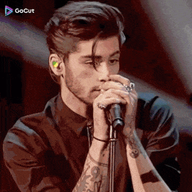 a man in a black shirt is singing into a microphone with a gocut logo in the background