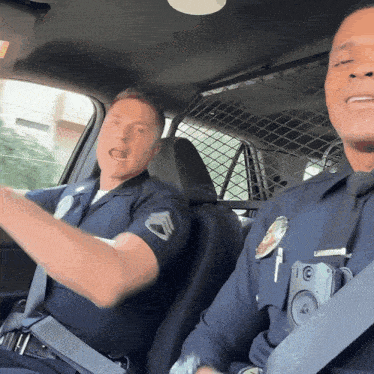 two police officers in a car with one wearing a badge that says ' l.a. police '