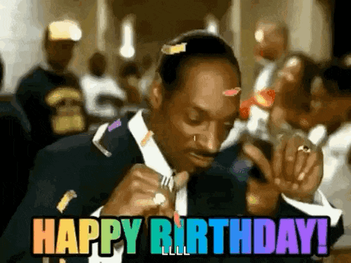 snoop dogg is wearing a suit and tie and smoking a cigarette and says `` happy birthday '' .